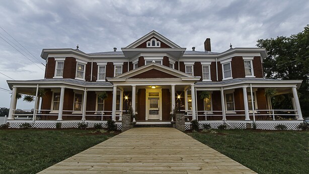 A large, two-story house with a central entrance, a porch, and a symmetrical facade.