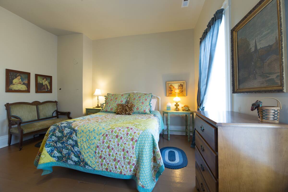 A bedroom with a bed, a nightstand, a dresser, and a chair.