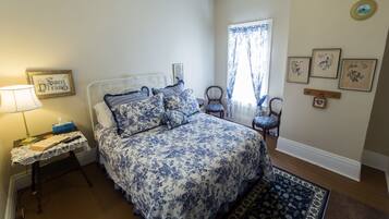 A bedroom with a bed, bedside table, lamp, and a window with curtains.