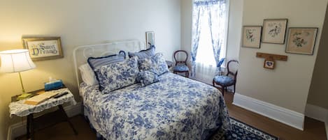Un dormitorio con cama, mesita de noche, lámpara y ventana con cortinas.