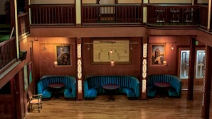 Un hall d’hôtel à plusieurs niveaux, doté d’un escalier en bois, d’un balcon avec des sièges et d’une table de billard.
