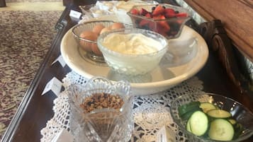 Uma mesa de buffet com diversos alimentos, incluindo frutas, nozes e uma tigela de iogurte.