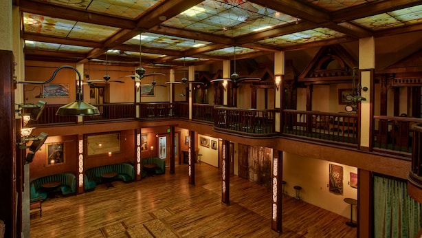 Un intérieur spacieux avec des planchers en bois, un balcon et un plafond orné de vitraux.