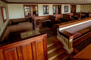 A hotel interior with wooden paneling, multiple seating areas, and a staircase.