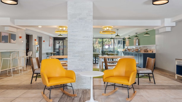 A modern interior with two rocking chairs, a white round table, and a kitchen area in the background. - Spark By Hilton Hilton Head Island (Hilton Head Island)