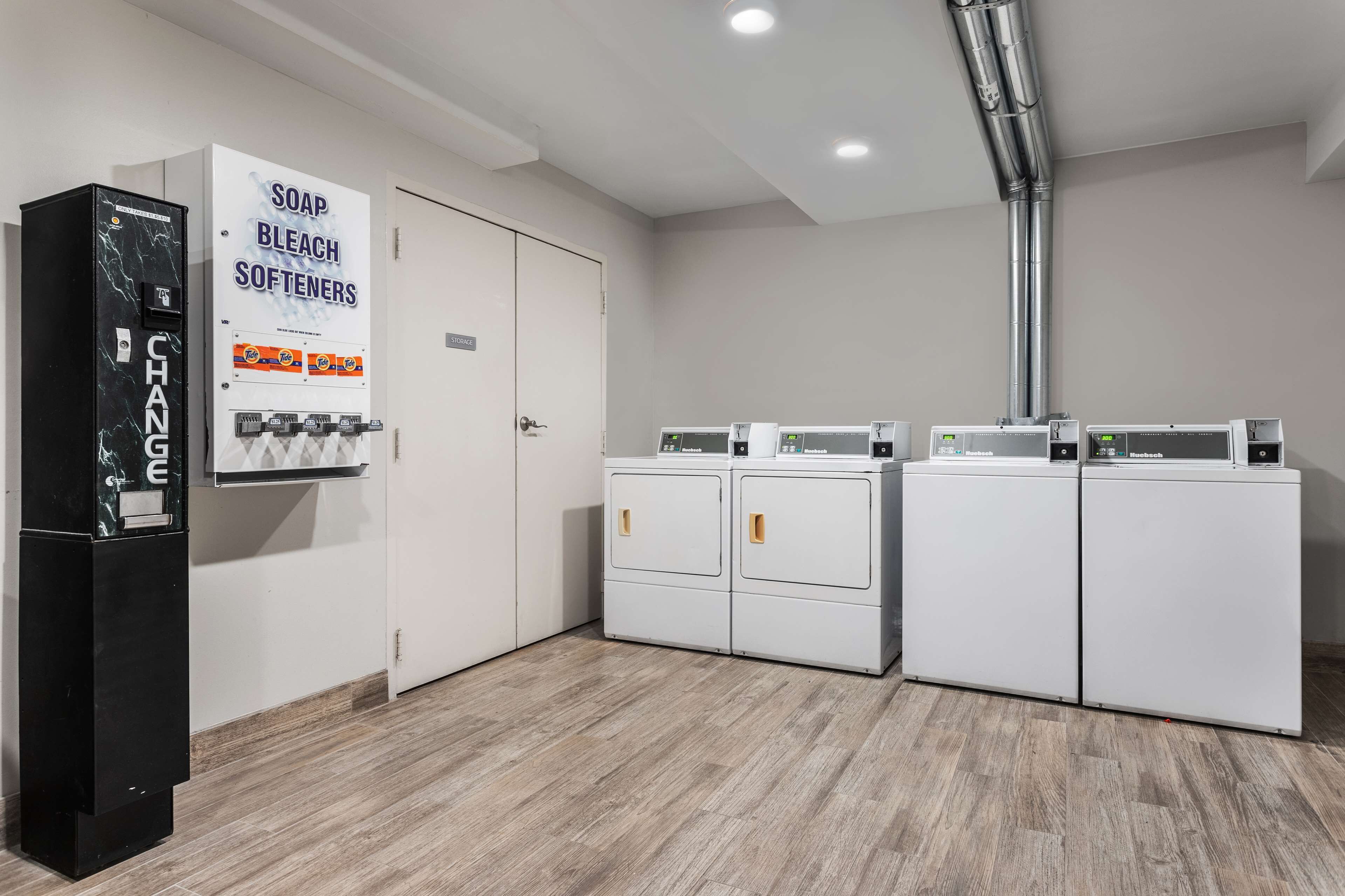 A laundry area with a soap and bleach softener dispenser, two washing machines, and a door.