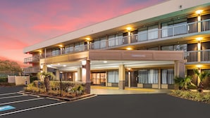 A multi-story hotel with a covered entrance, outdoor parking, and a clear sky. - Spark By Hilton Hilton Head Island (Hilton Head Island)