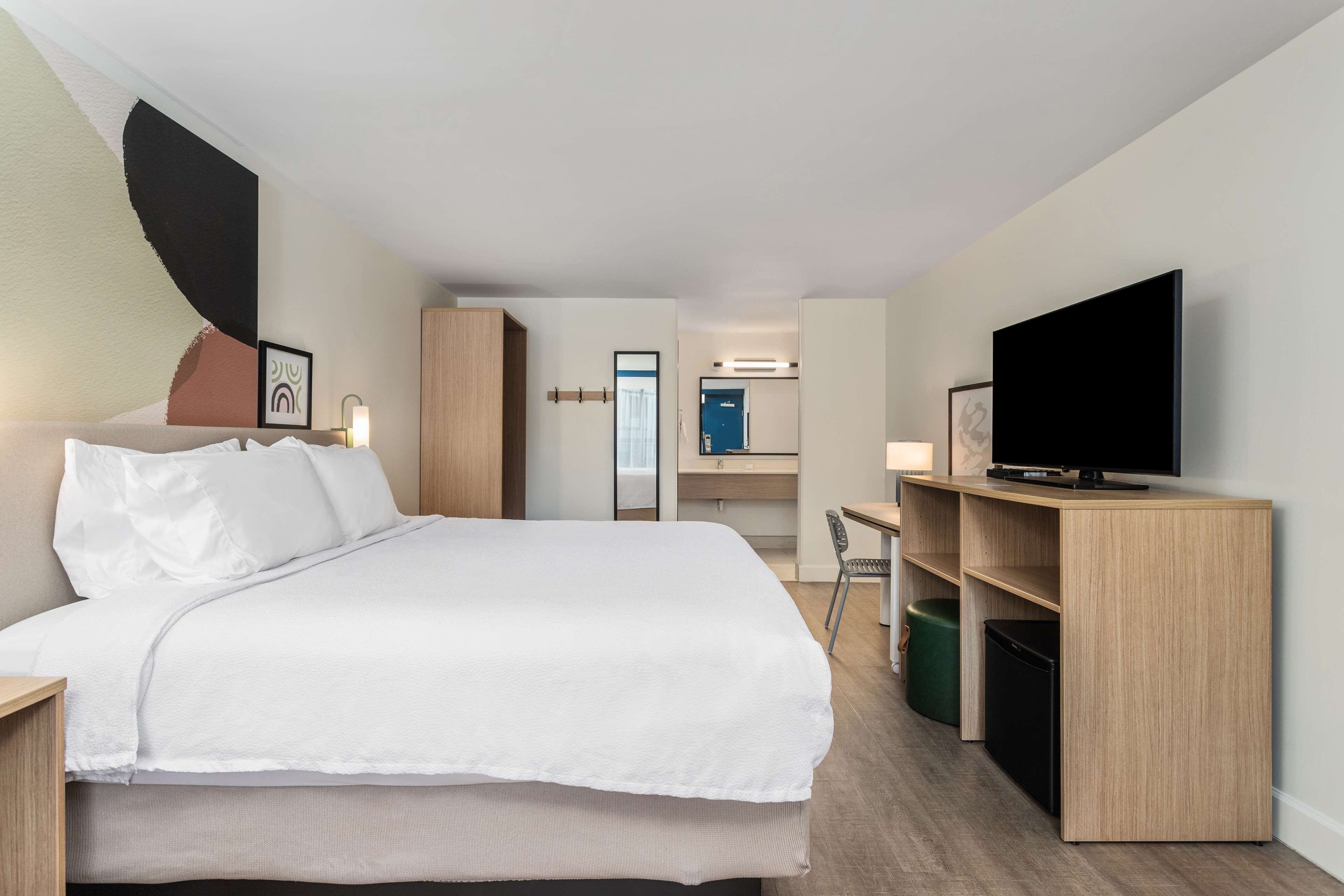 A hotel room with a bed, a desk, a television, and a wardrobe.