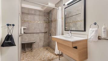 A modern bathroom with a shower, vanity, and a large mirror.