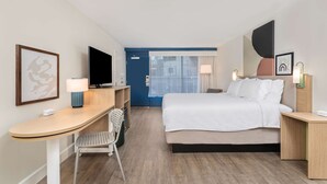 A hotel room with a bed, desk, chair, television, and a door leading to a balcony. - Spark By Hilton Hilton Head Island (Hilton Head Island)