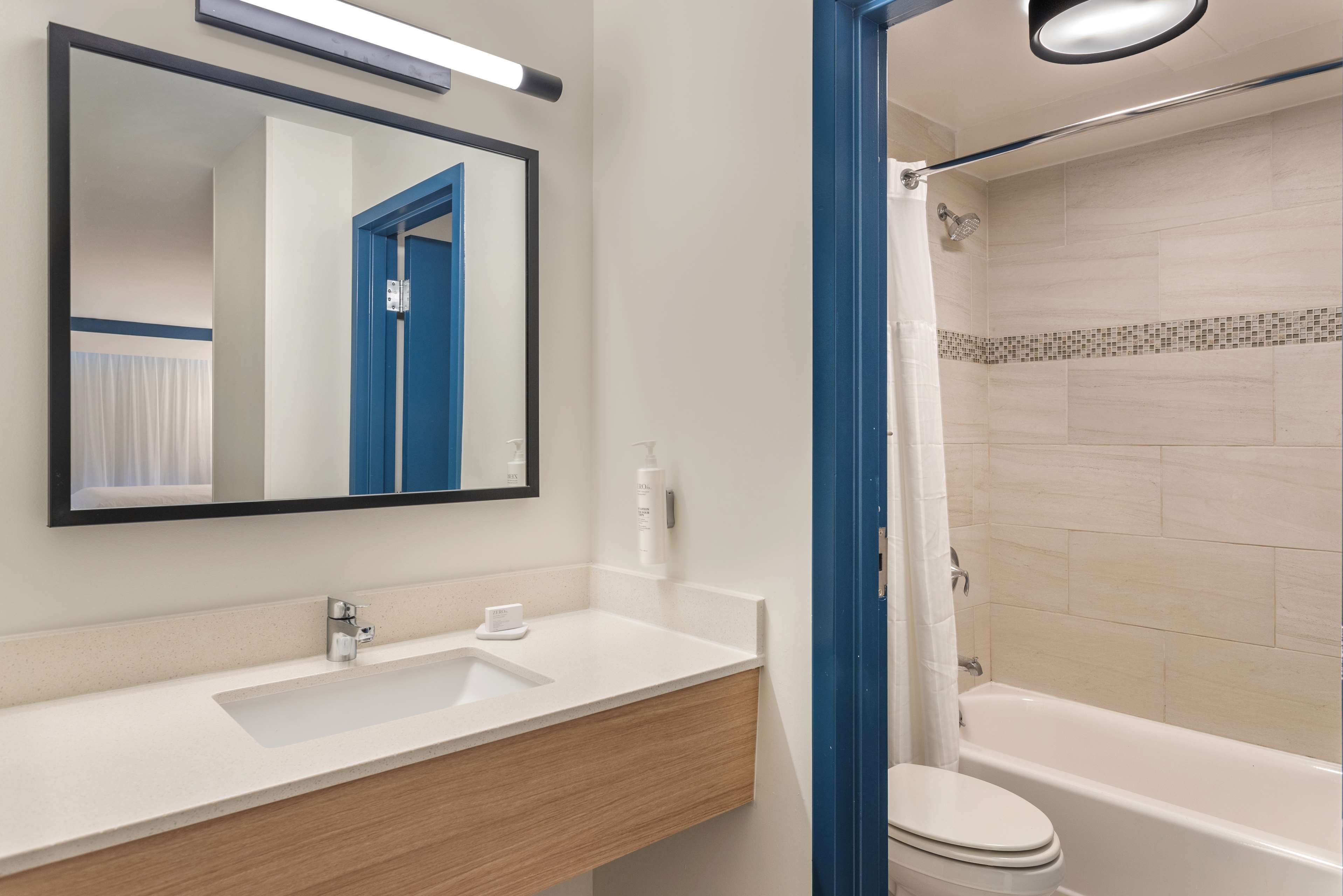A bathroom with a white sink, a mirror, a toilet, and a shower area.