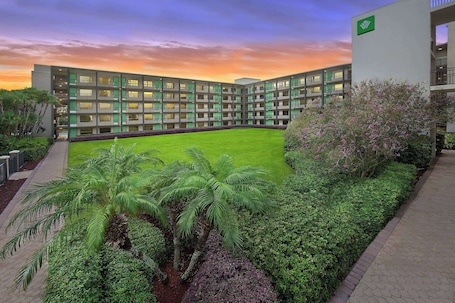 A modern building with a courtyard, surrounded by lush greenery and a well-maintained lawn.. Wyndham Garden Lake Buena Vista – Disney Springs® Area
