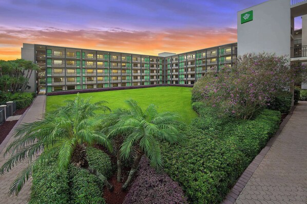 A modern building with a courtyard, surrounded by lush greenery and a well-maintained lawn. - Wyndham Garden Lake Buena Vista – Disney Springs® Area (Lake Buena Vista)