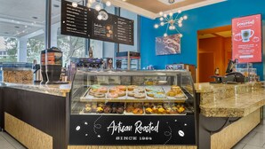 A bakery counter with a variety of pastries and a menu board above it. - Wyndham Garden Lake Buena Vista – Disney Springs® Area (Lake Buena Vista)