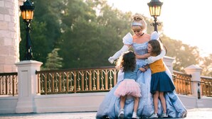A person in a blue dress with a pink skirt standing on a bridge with a railing. - Wyndham Garden Lake Buena Vista – Disney Springs® Area (Lake Buena Vista)