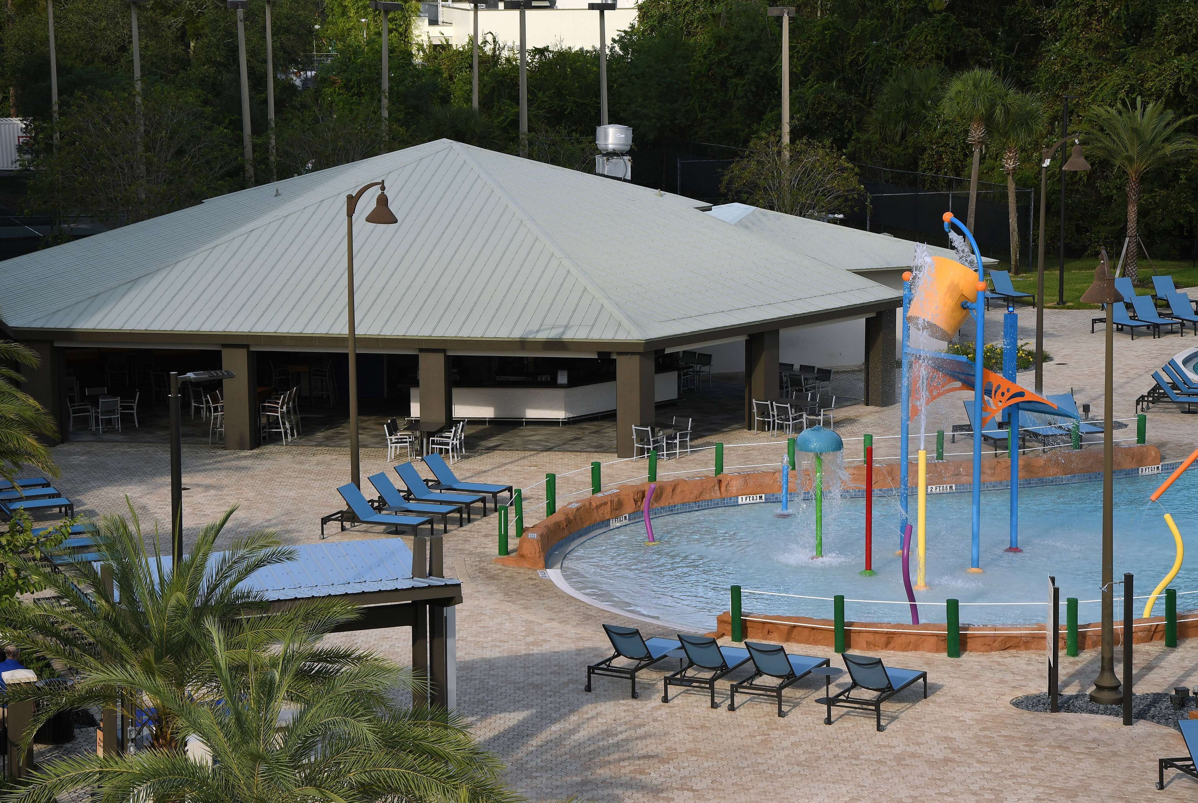 A covered pool area with lounge chairs and a water play structure.