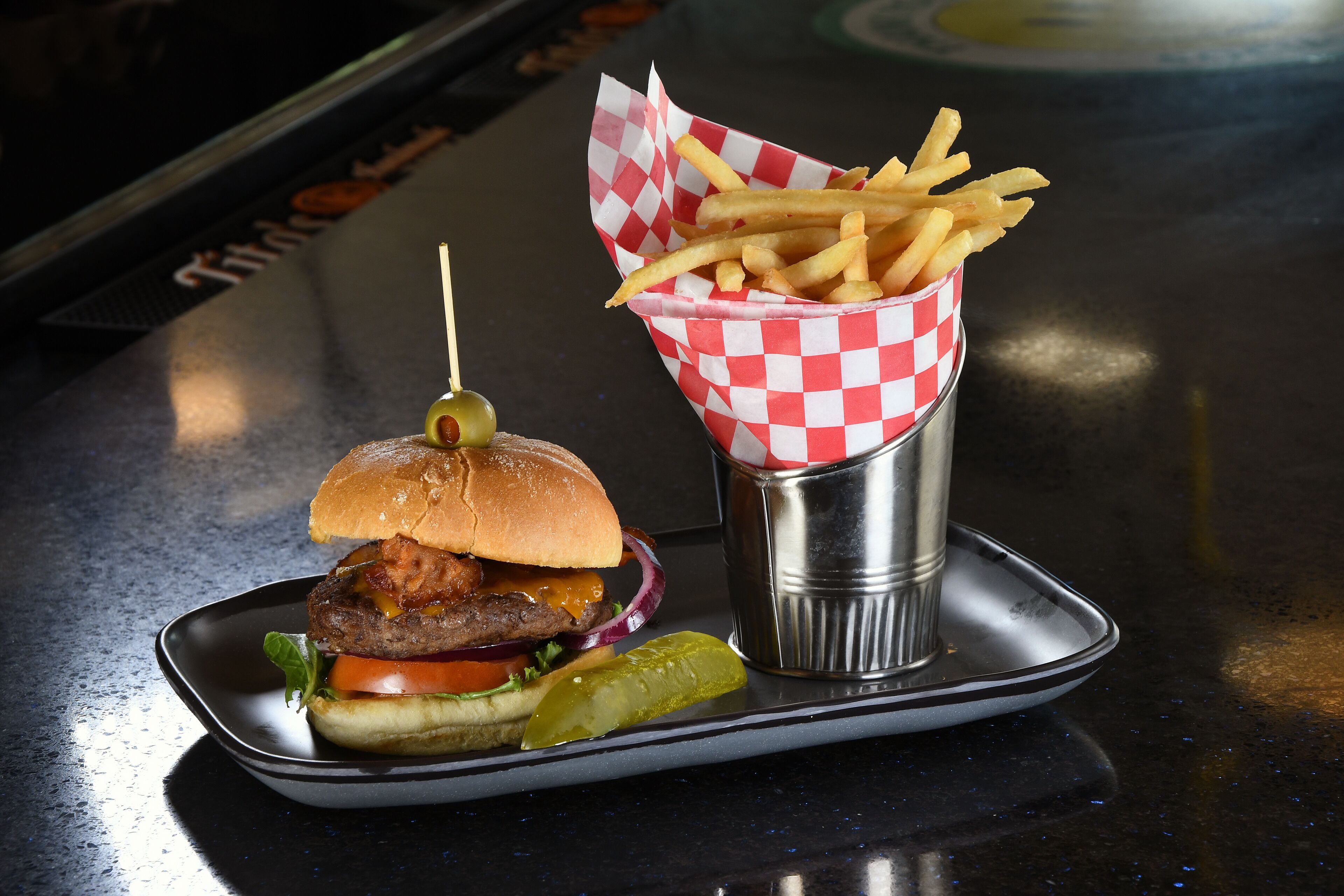 A burger with fries and a pickle on a tray.