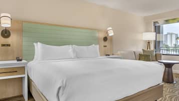 A hotel room with a large bed, wooden headboard, bedside tables, and a view of buildings through the window.