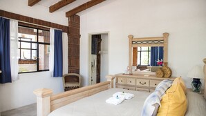 A bedroom with a bed, a dresser, a mirror, and a window with curtains.