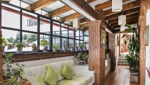 A cozy interior with a sofa, potted plants, and a brick column.