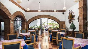 A restaurant with brick arches, tiled floors, and tables with blue tablecloths.