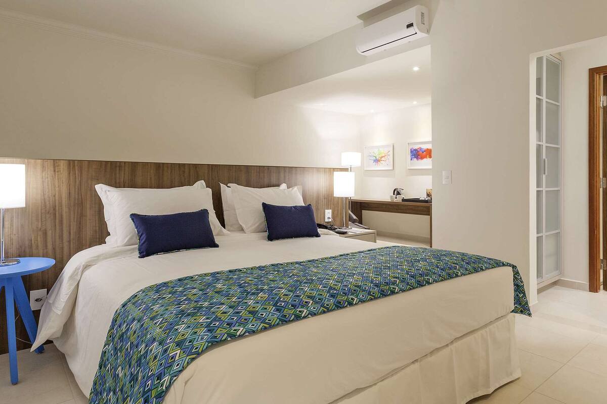 A hotel room with a large bed, a bedside table with a lamp, and a wooden headboard.