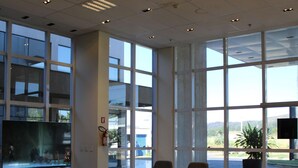 Un vestíbulo amplio con un televisor de pantalla plana grande, asientos cómodos y ventanas grandes con vistas al exterior.