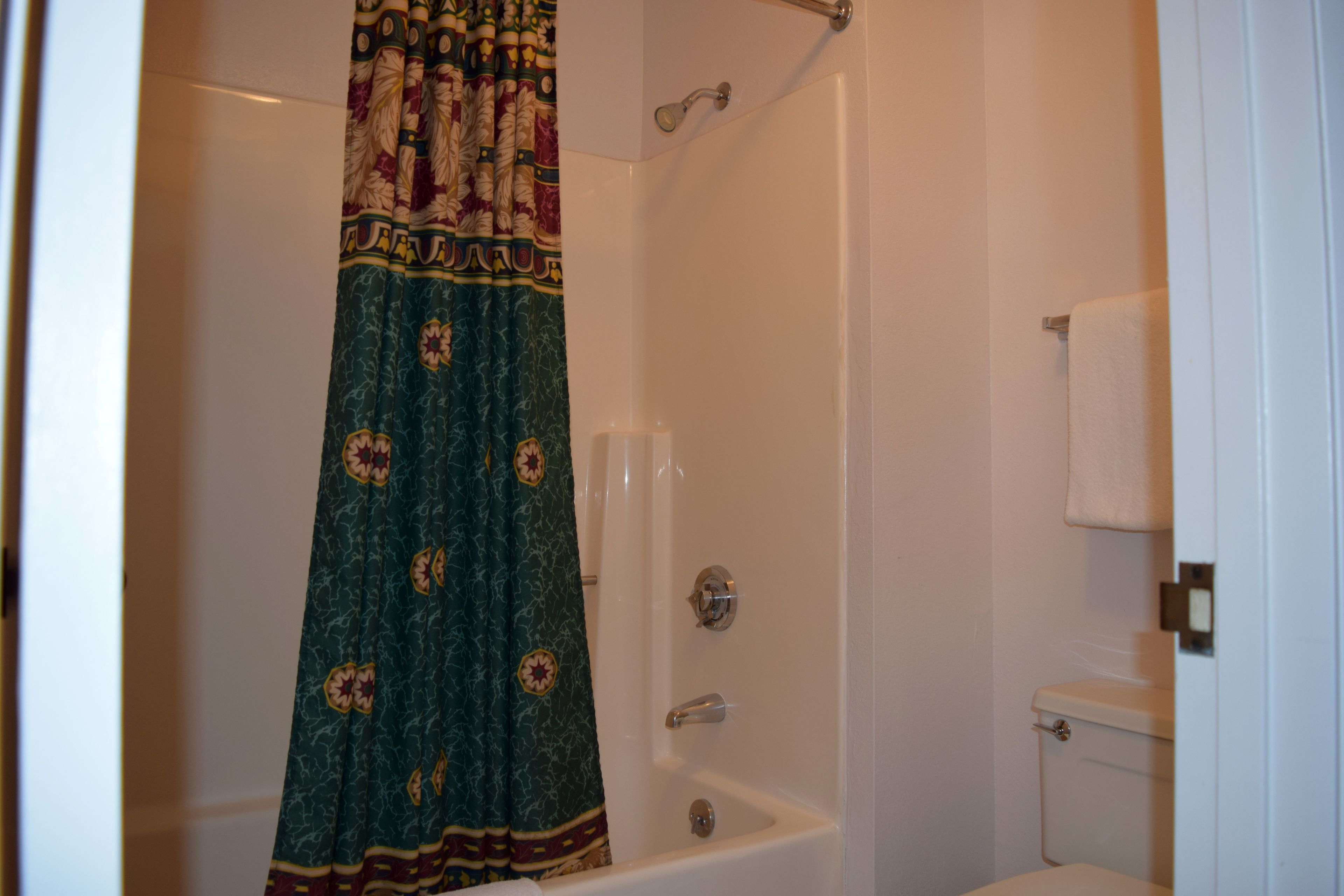 A bathroom with a shower curtain, a bathtub, and a toilet.
