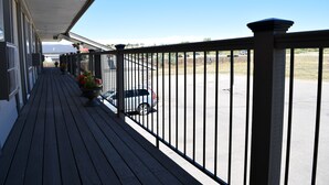 A wooden deck with a railing, potted plants, and a view of a parking lot and distant mountains. - Littletree Inn (Granby)