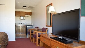 A hotel room with a television, wooden furniture, a microwave, and a kitchen area. - Littletree Inn (Granby)
