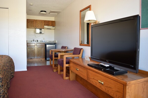 Habitación de hotel con televisión, muebles de madera, microondas y zona de cocina.