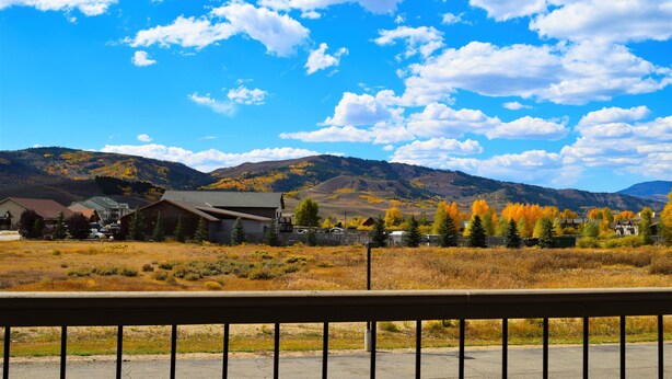 A rural landscape with a clear sky, mountains, and a fenced area with buildings. - Littletree Inn (Granby)