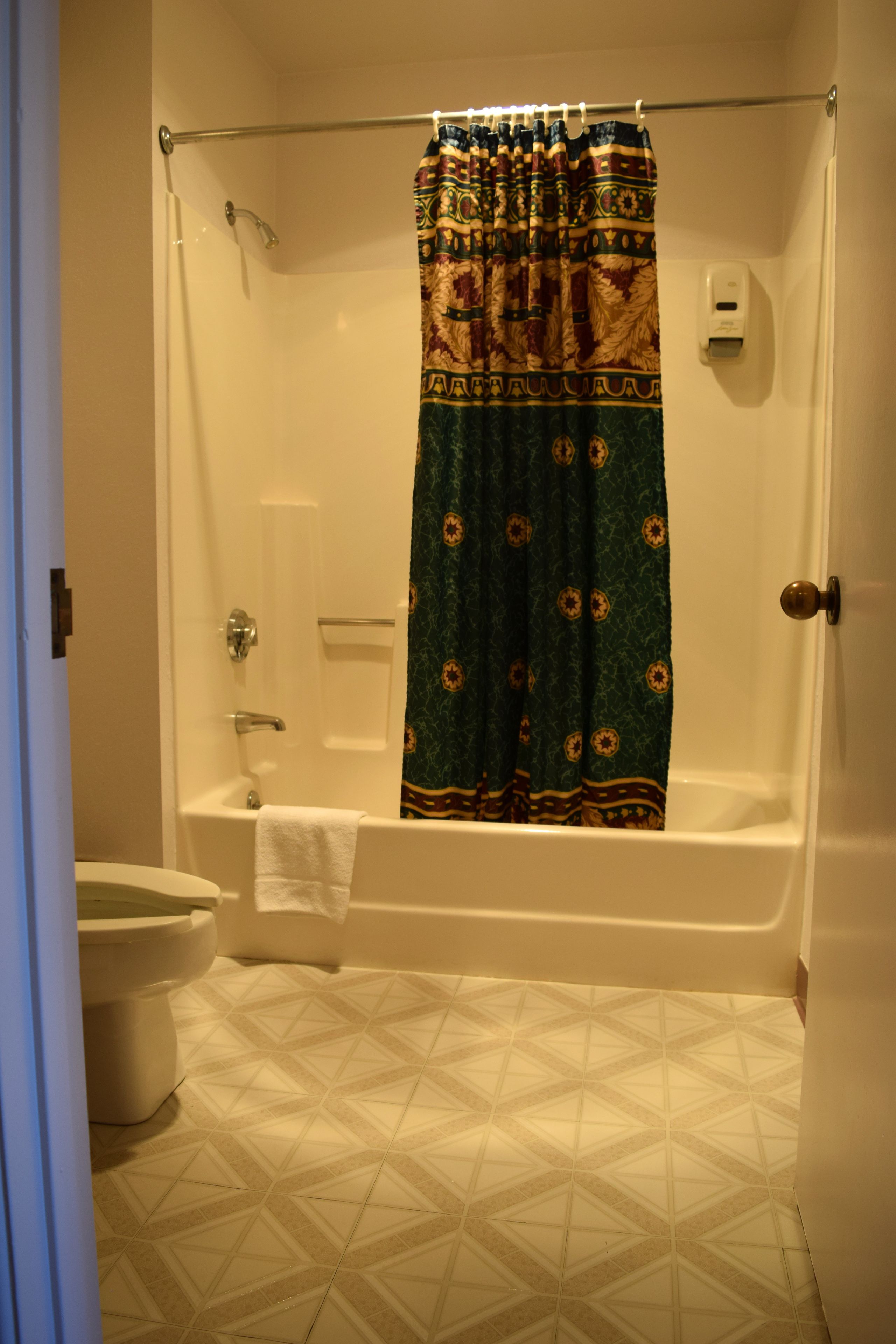 A bathroom with a shower curtain, a toilet, and a bathtub.