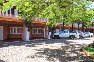 Una hilera de edificios de una sola planta con camino de grava y vehículos estacionados.