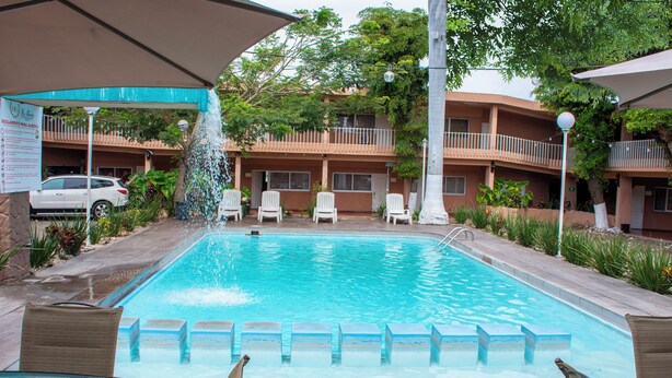 Una piscina con sillas de descanso y una fuente.