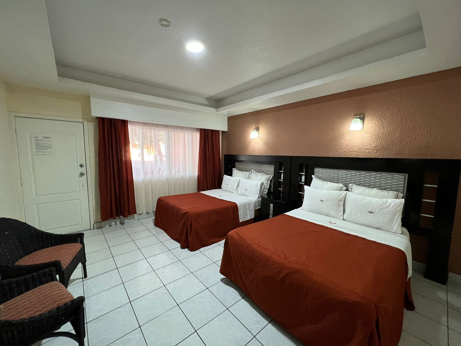 Una habitación de hotel con dos camas, una silla y una ventana con cortinas.