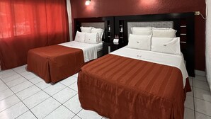 Habitación de hotel con dos camas, cortinas rojas, suelo de baldosas y una lámpara en el techo.