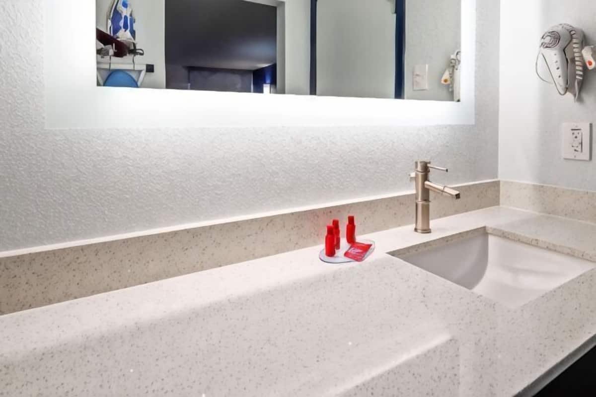 A bathroom with a white speckled countertop, a single faucet, and a mirror above the sink.
