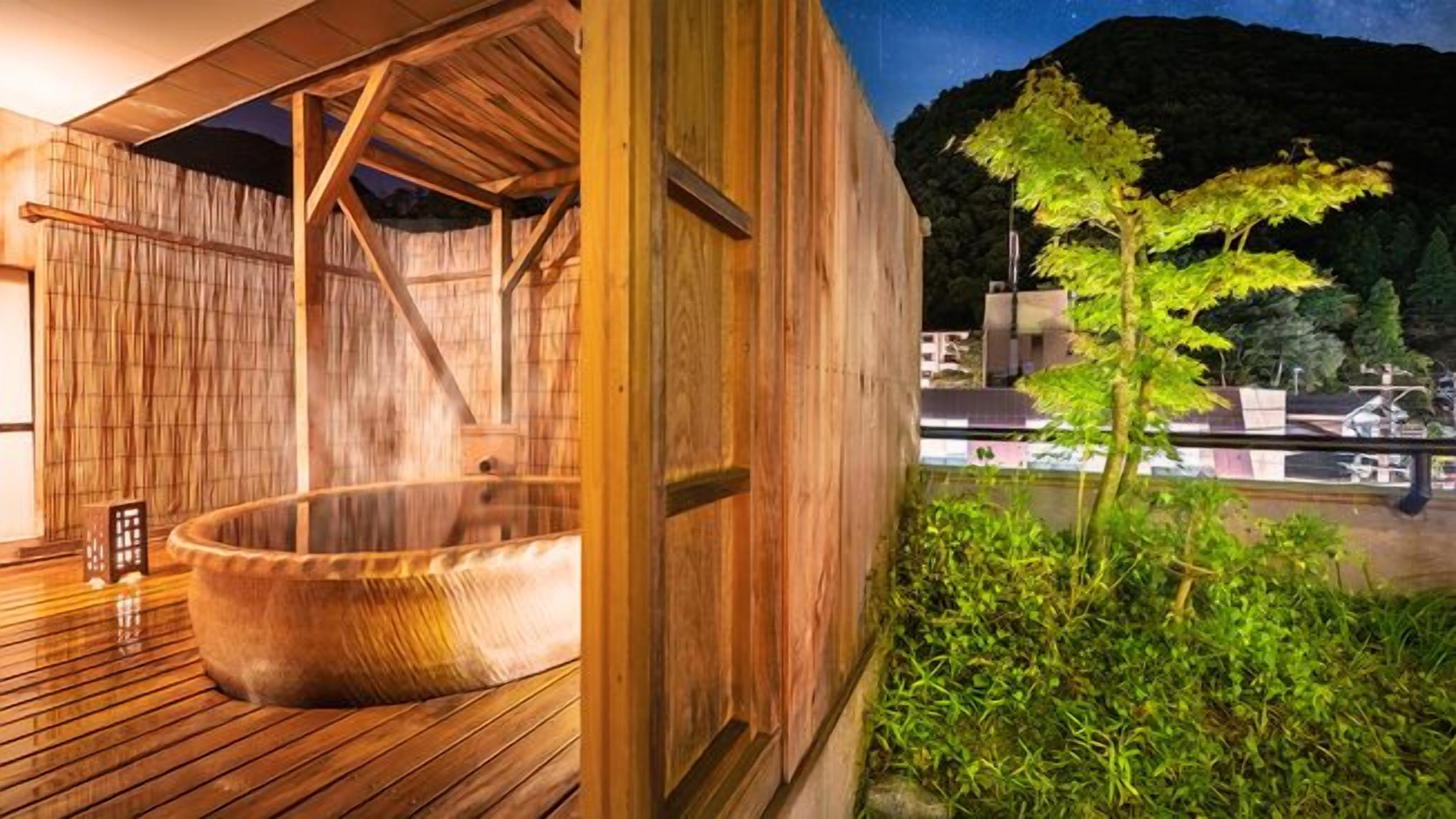 A wooden spa building with a hot tub and a view of a mountain.