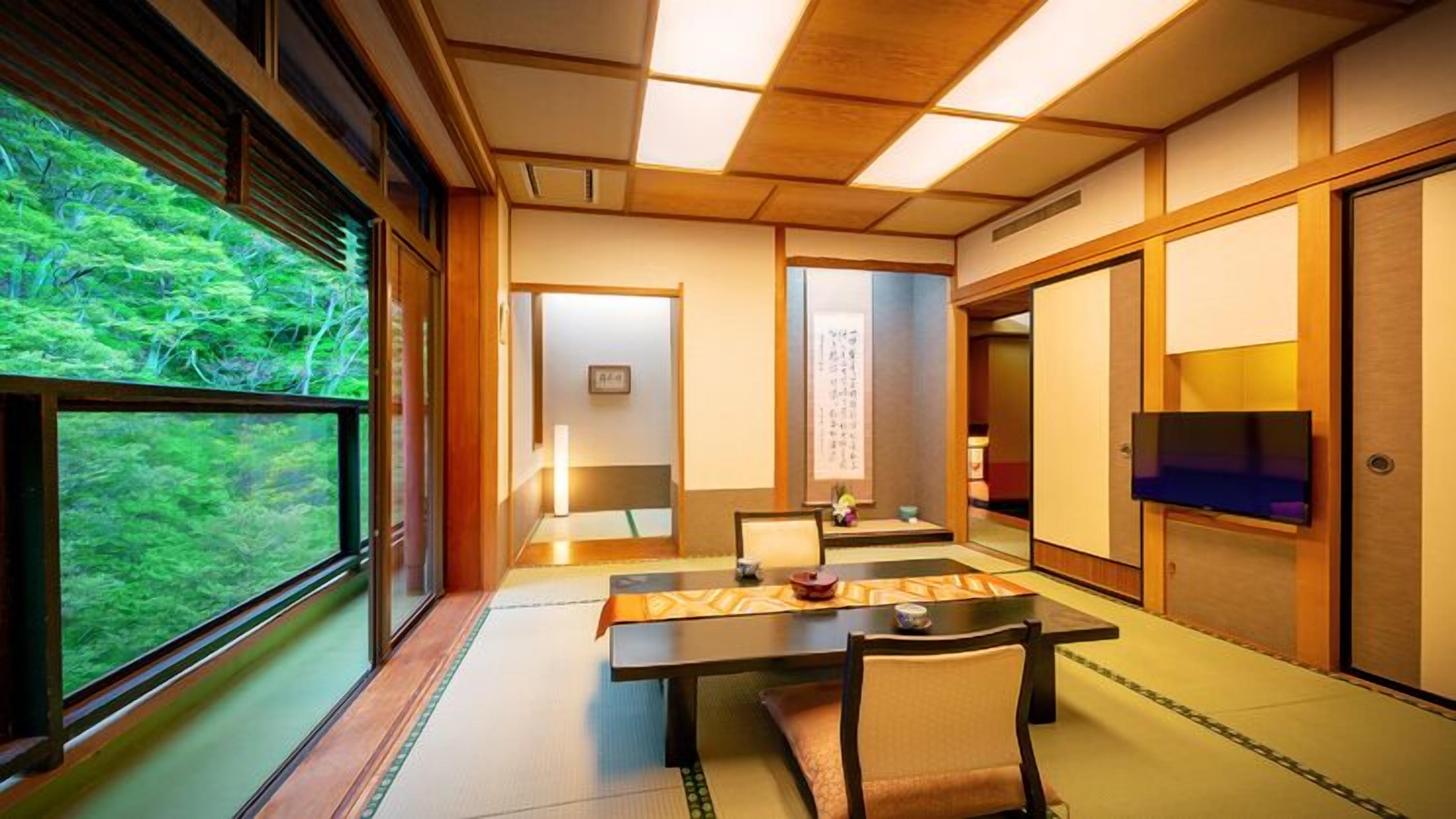 A traditional Japanese room with tatami flooring, a low table with a cushion, a television, and sliding doors.