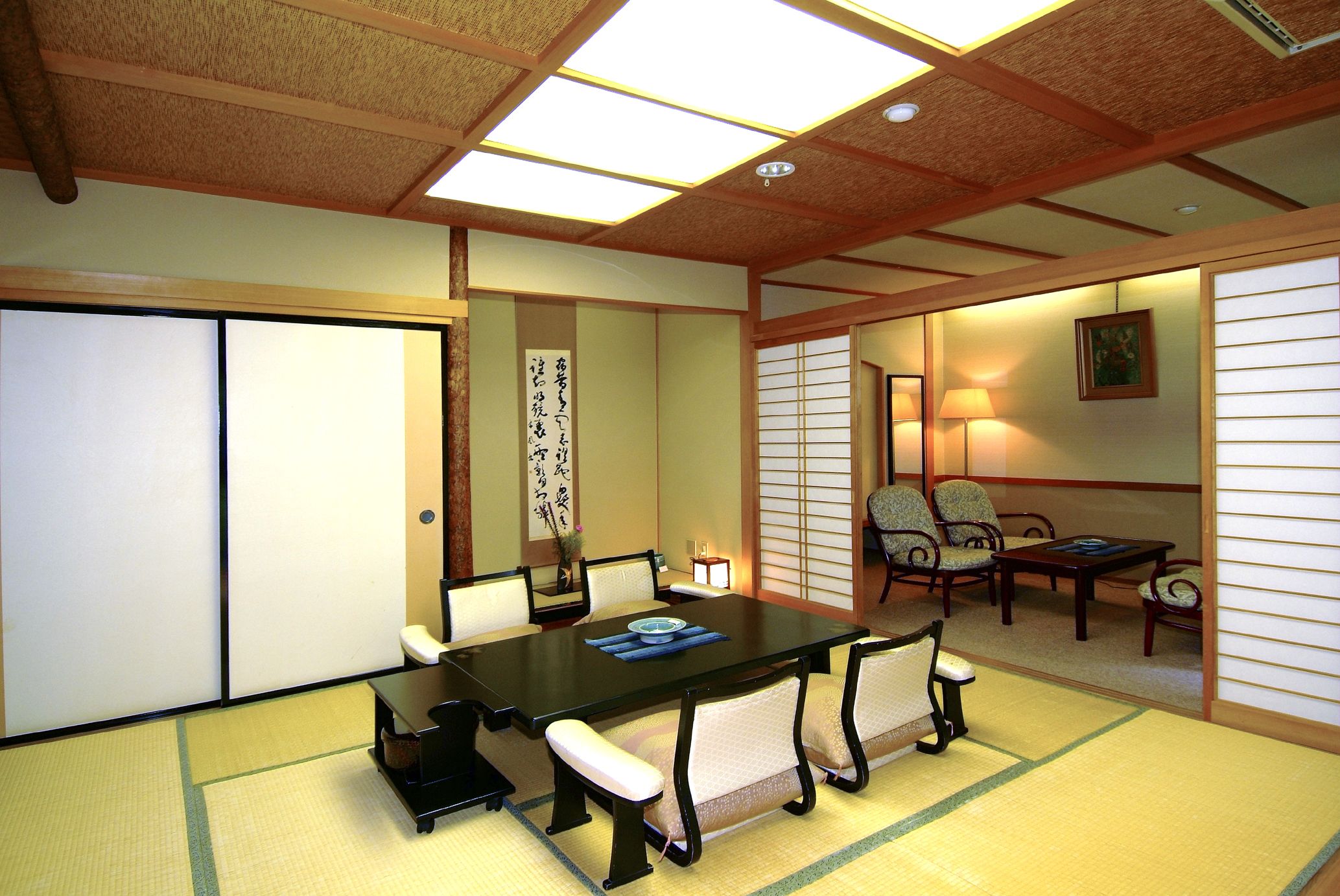 A traditional Japanese room with tatami flooring, a low table with cushions, and sliding doors.