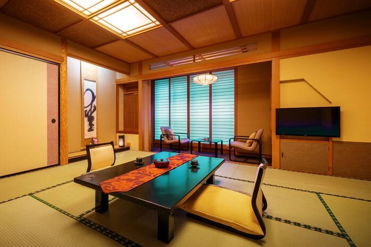 Une pièce de style japonais traditionnel, avec un sol recouvert de tatamis, une table basse et des portes coulissantes.