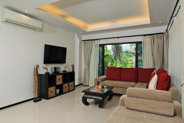 A modern living room with a sofa, armchairs, a coffee table, and a TV. - Thaimond Residence by TropicLook (Rawai)