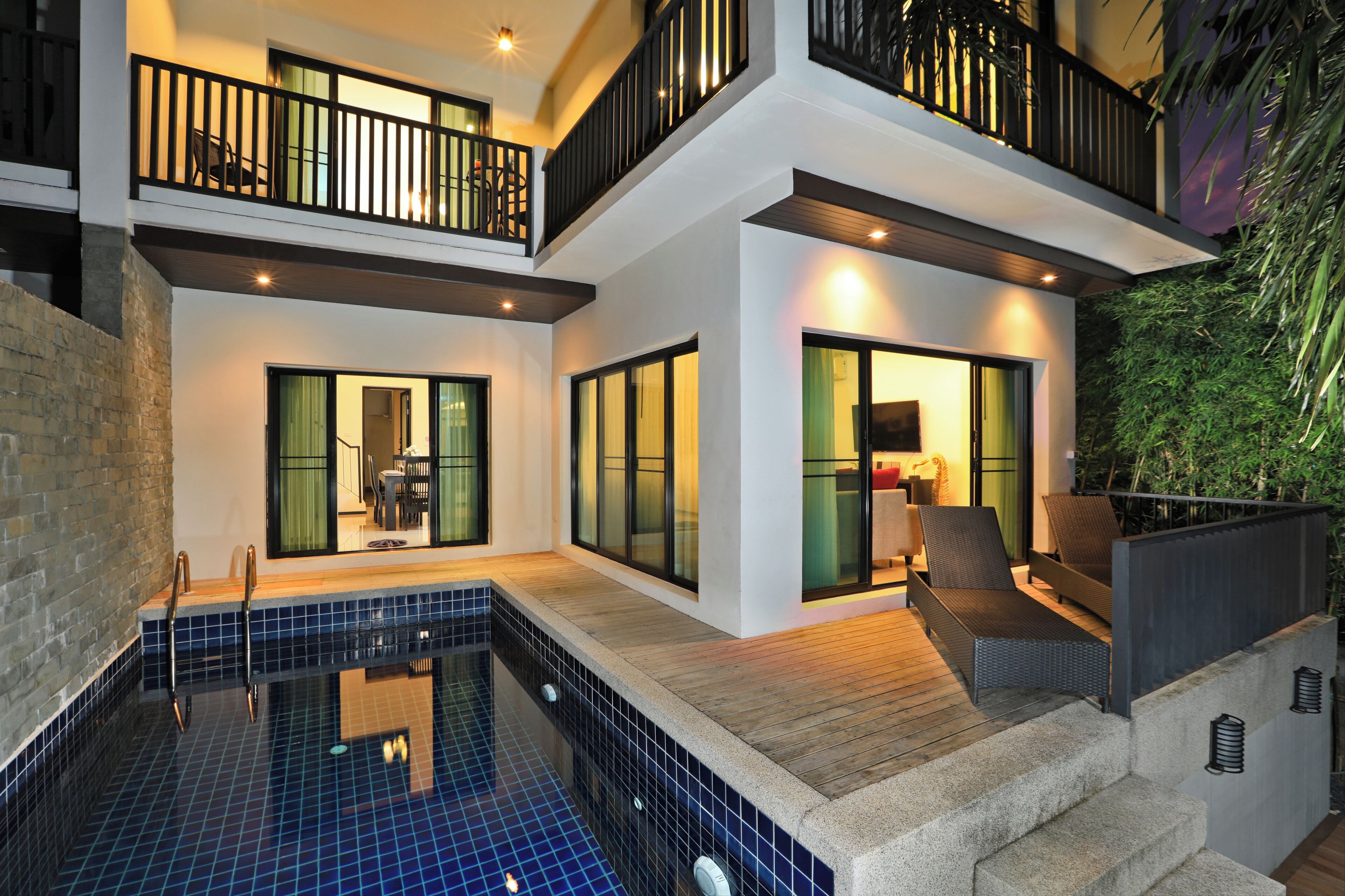 Una casa moderna de dos plantas con piscina, ventanas amplias y un balcón.