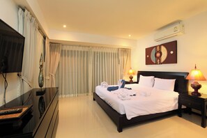 Habitación de hotel con cama, lámparas de noche, un televisor de pantalla plana, un adorno de pared y un ventanal con cortinas.