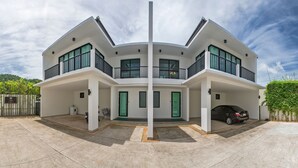 Una casa moderna de dos pisos con fachada curva, ventanas amplias y un coche en la entrada.
