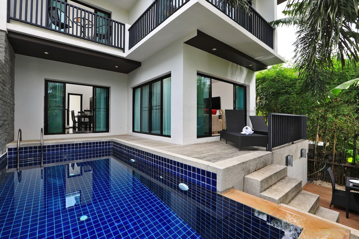 A modern house with a swimming pool, large windows, and a balcony.