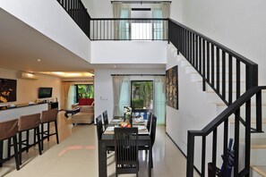 A spacious living area with a dining table, chairs, and a staircase. - Thaimond Residence by TropicLook (Rawai)