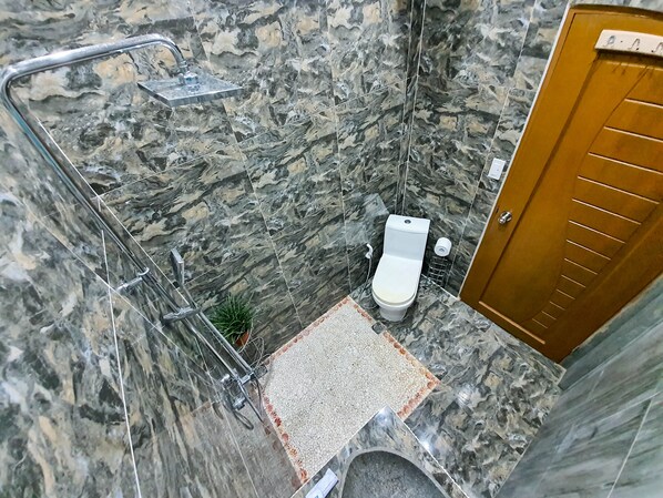 A bathroom with a toilet, shower, and a wooden door. - Kaiyana Boracay Beach Resort (Boracay Island)