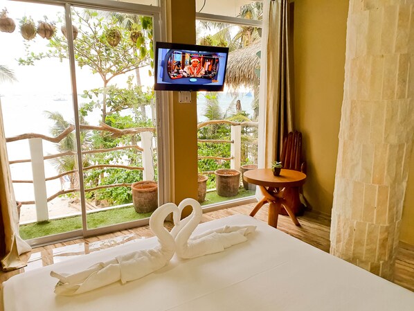A hotel room with a bed, a TV, a balcony with plants, and a view of the sea. - Kaiyana Boracay Beach Resort (Boracay Island)